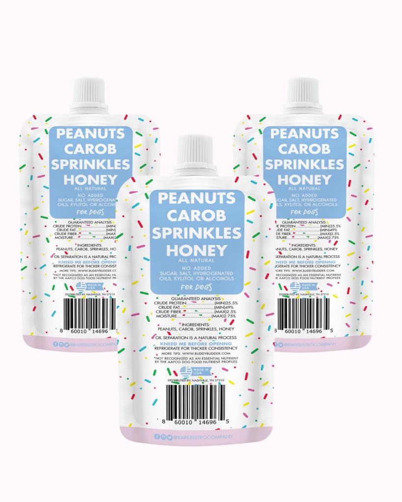 Birthday Bash Buddy Budder trio of 4oz all natural dog peanut butter squeeze packs with peanuts, carob, sprinkles, and honey in colorful packaging.